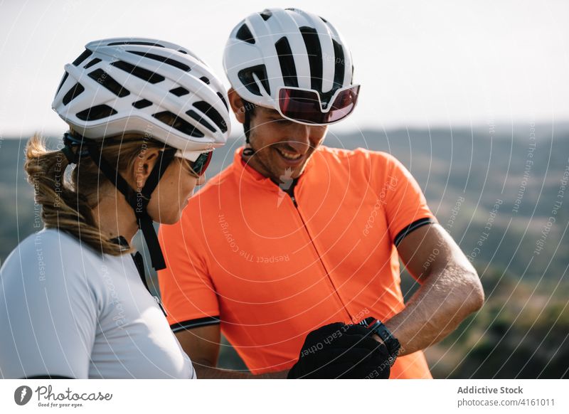 Zwei Radfahrer, die die Zeit auf ihrer Armbanduhr überprüfen Zusammensein Paar intelligente Uhr Zeitmanagement Genauigkeit Apparatur Gerät Hügel punktuell