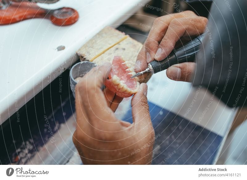 Crop Mann mit Maschine Polieren künstliche Kiefer Zahnersatz dental Techniker Zähne polnisch Prothesen männlich Arbeit Labor professionell Werkzeug Beruf Gerät