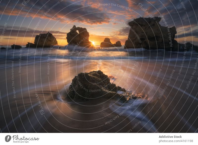 Felsen auf welligem Meer unter Himmel mit glänzender Sonne wolkig Bewegung Natur fließen schnell Sonnenuntergang Meereslandschaft Sonnenschein Wasser