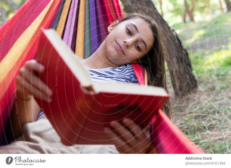 Entspannte Frau liest Buch in Hängematte lesen Etage genießen Sommer Lügen Park Literatur interessant friedlich Roman ruhig lässig Hobby Natur Erholung