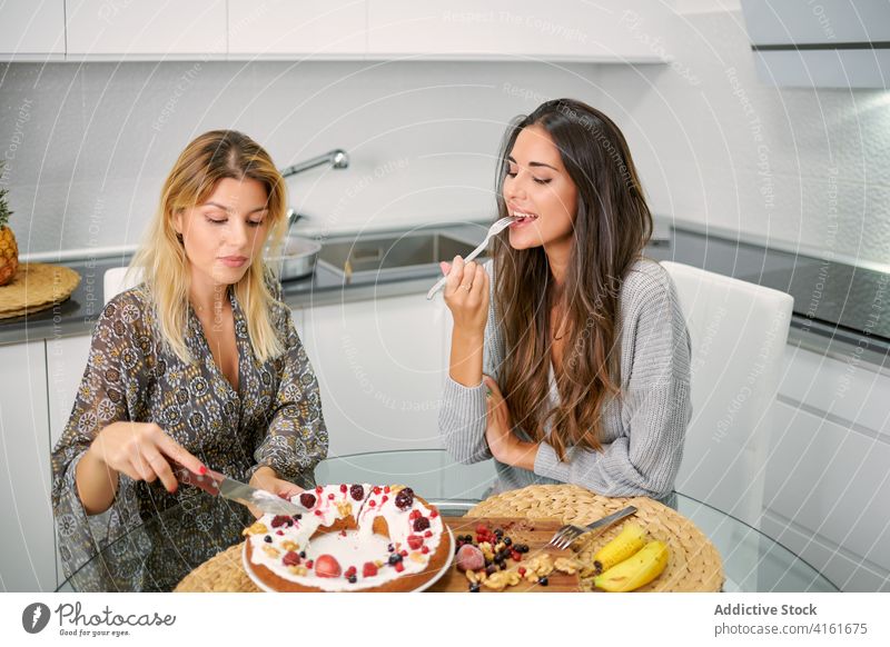 Glückliche Frauen essen veganen Nachtisch in der Küche gesunde Ernährung Kuchen Veganer Dessert genießen Gebäck selbstgemacht Diät Beeren jung Lebensmittel süß