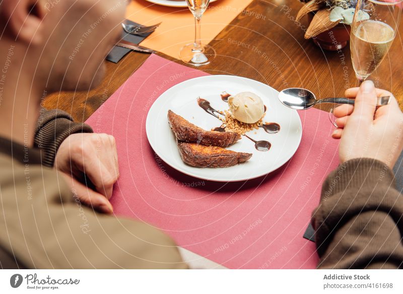 Crop-Mann mit süßem Dessert im Café Speiseeis Baggerlöffel Kuchen Biskuit dienen schmackhaft männlich Tisch appetitlich lecker geschmackvoll Lebensmittel