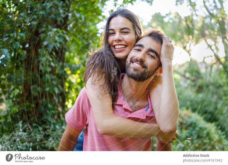 Verspieltes junges ethnisches Paar hat Spaß im Park Glück Liebe Partnerschaft spielerisch Spaß haben Huckepack romantisch Gesicht berühren Lächeln Zuneigung