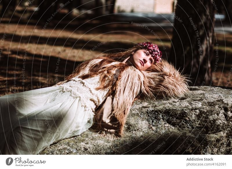 Sinnliche Frau in traditioneller nordischer Tracht auf einem Stein liegend Tradition Mode Stil sinnlich verträumt Hochzeit Fell Outfit skandinavisch charmant