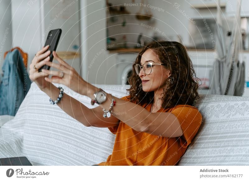 Junge Frau nimmt Selbstporträt auf Smartphone liegend auf Sofa Selfie Lügen sich[Akk] entspannen soziale Netzwerke Komfort benutzend Apparatur heimwärts Gerät