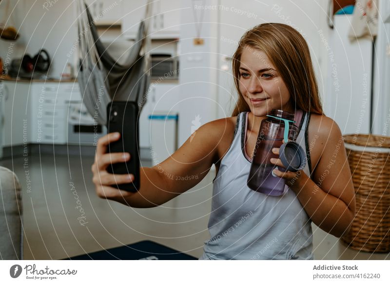 Zufriedene Sportlerin mit Wasserflasche, die ein Selfie mit ihrem Smartphone macht Vitalität Energie Training Lächeln Inhalt Hydrat Getränk üben Flasche