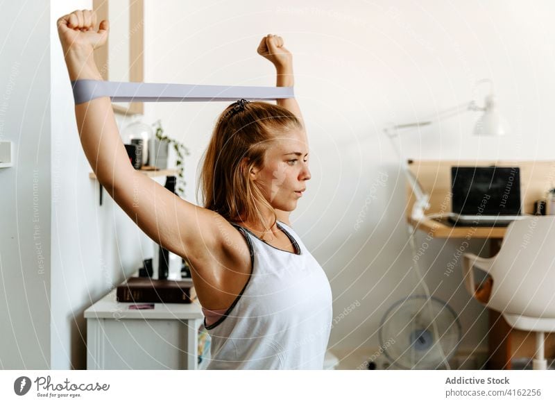 Sportlerin beim Training mit Gummiband zu Hause Übung Widerstandsband Vitalität Energie üben schlank Frau Aktivität physisch Sportbekleidung Wellness Fitness