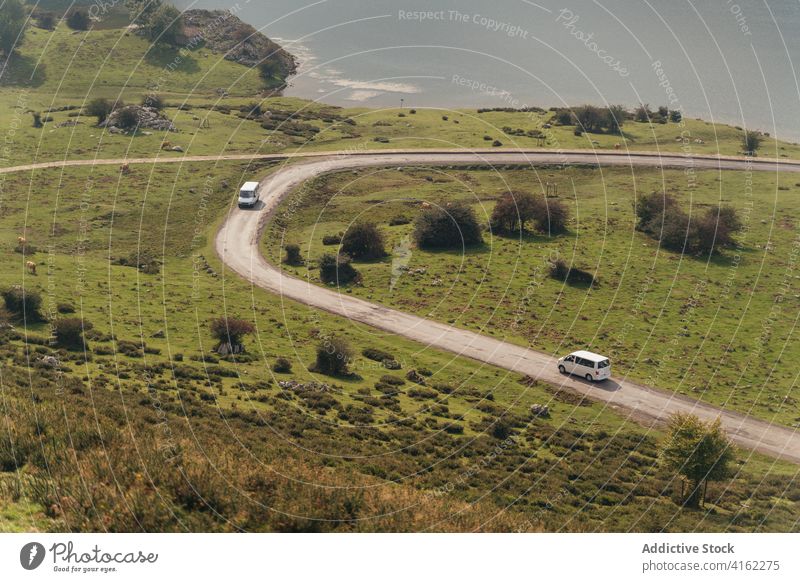 Autos auf der Landstraße in einem grünen Tal in der Nähe eines Teichs ländlich PKW Straße Gelassenheit Natur Umwelt üppig (Wuchs) malerisch Laufwerk Hügel