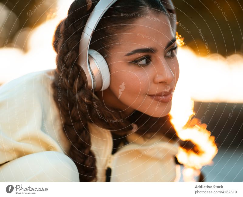 Trendige weibliche Millennials hören Musik beim Longboardfahren im Park Frau Mitfahrgelegenheit zuhören positiv aktiv trendy Freude modern Sonnenuntergang jung