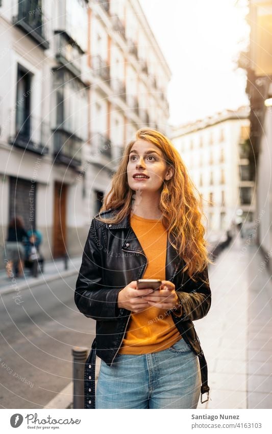 Ingwer Kopf Frau Porträt Mädchen per Telefon Ingwer-Kopf hübsch jung Straße Großstadt Vorderansicht außerhalb Tippen Funktelefon Blick Smartphone benutzend