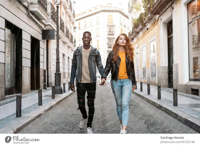 Lovely Couple Holding Hands laufen Händchenhalten Vorderansicht Straße Blick auf die Front Porträt Partnerschaft multirassisch Schwarzer Mann Kaukasier