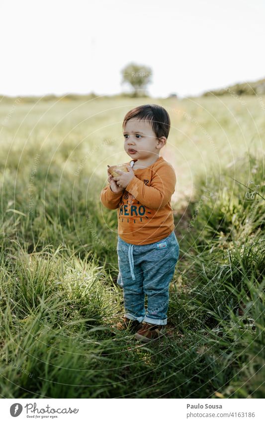 Kind isst Obst Junge 1-3 Jahre Kaukasier Essen Frucht Feld Frühling Tag Farbfoto Kindheit Kleinkind Mensch Außenaufnahme Spielen Leben mehrfarbig Freude Natur