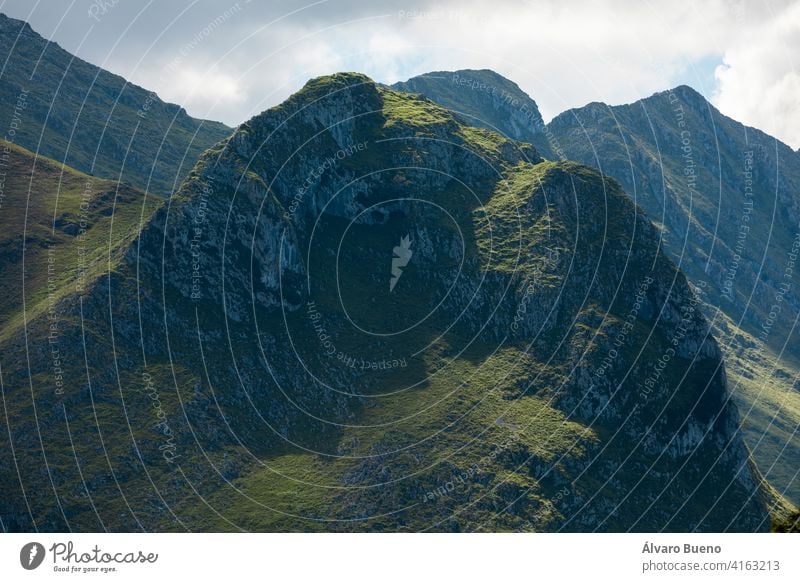 Riesige grüne Berge, schöne und erstaunliche ferne Gipfel, von der Sonne beleuchtet, im Nationalpark Picos de Europa, gesehen von Llanes, in der Nähe der Küste, in Asturien, Spanien.