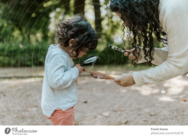 Mutter mit Tochter spielt mit Lupe Mutterschaft Mutter mit Kind Kaukasier 1-3 Jahre Bildung erkunden Lupeneffekt Nahaufnahme Blick Farbfoto Glas vergrößert