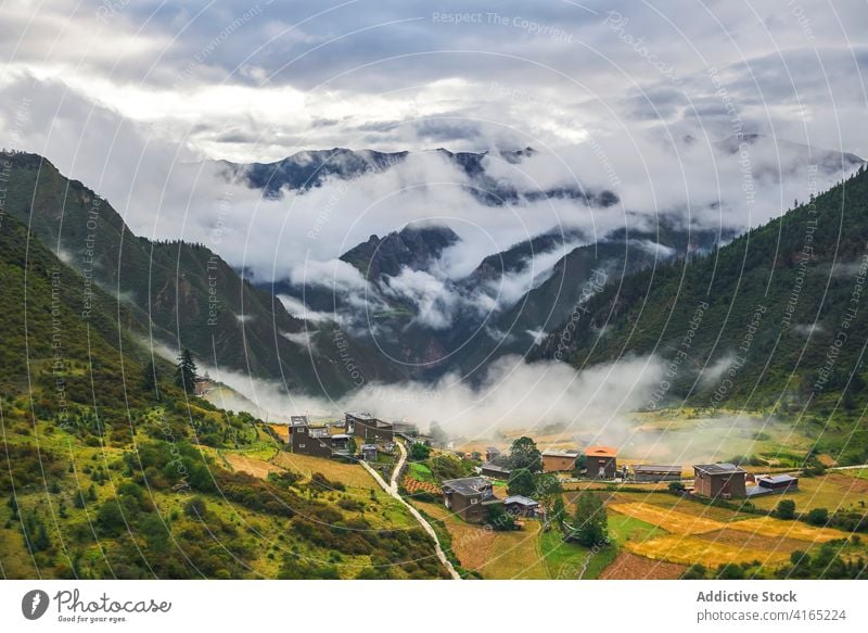 Kleines asiatisches Dorf inmitten hoher, wolkenverhangener Berge Hochland Umwelt Ambitus wolkig Höhe Stadt Natur Berge u. Gebirge Landschaft Tal Gipfel Pflanze