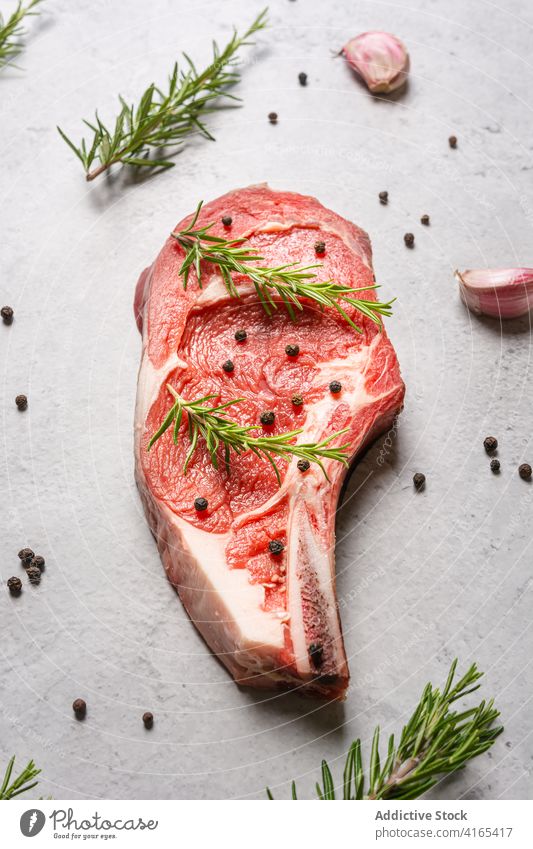 Rohes Rindersteak mit Kräutern auf dem Tisch Rindfleisch Steak roh Knochen t Knochen Rosmarin Garnierung Fleisch Paprika schwarz Küche Koch Lebensmittel lecker