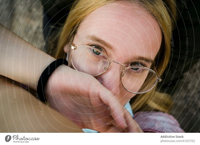 Junge Frau mit Brille schaut in die Kamera blond Windstille ruhen sich[Akk] entspannen jung Porträt ruhig Stil Spektakel Gelassenheit tausendjährig Jugendlicher