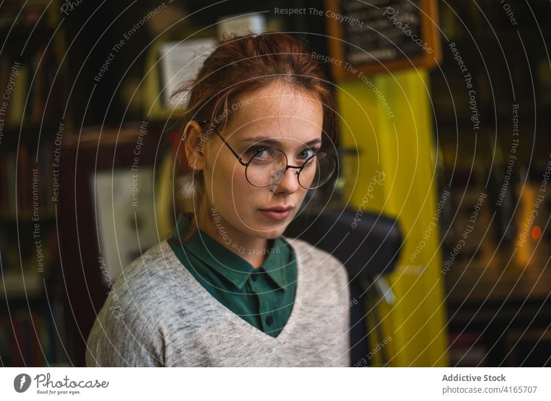 Stilvolle Frau mit Brille in der Bibliothek Bücherregal klug ernst jung gemütlich Bücherschrank intelligent lernen Buch Literatur clever Wissen Bildung