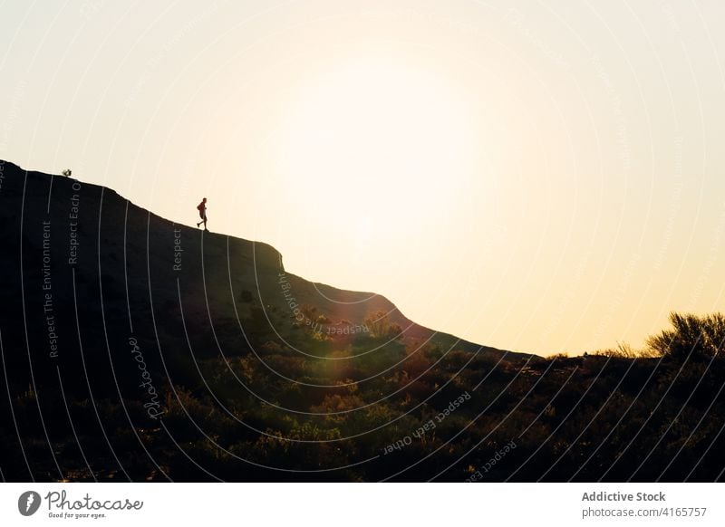 Anonyme Person, die bei Sonnenuntergang auf einem Hügel läuft laufen Berge u. Gebirge Berghang Training Athlet Aufstieg Silhouette Übung Gesundheit Sport