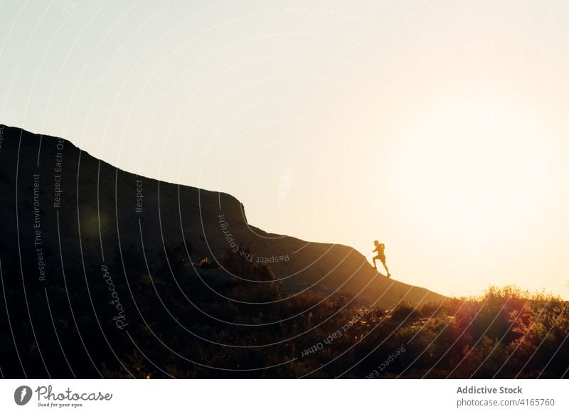 Anonyme Person, die bei Sonnenuntergang auf einem Hügel läuft laufen Berge u. Gebirge Berghang Training Athlet Aufstieg Silhouette Übung Gesundheit Sport