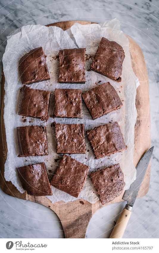 Leckere hausgemachte Brownies auf Pergament in der Küche Spielfigur selbstgemacht Dessert gebacken Leckerbissen süß geschmackvoll Schneidebrett Messer