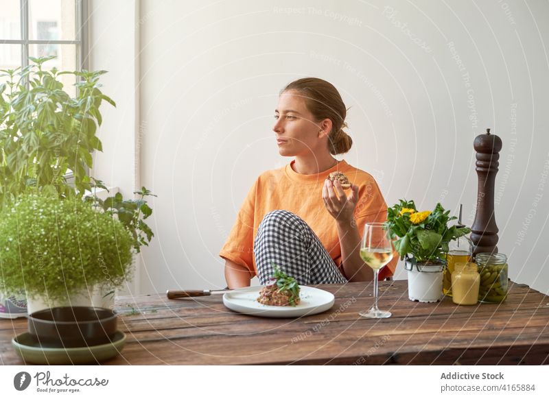 Nachdenkliche Frau mit leckerem Mittagessen zu Hause Steak Tartar heimwärts Wein trinken genießen Wochenende Speise Freude Teller Tisch Lächeln ruhen Glück