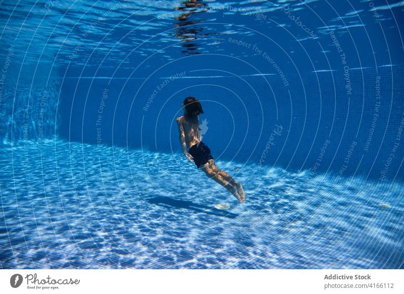 Teenager-Junge taucht ins Poolwasser Energie Sinkflug schwimmen aktiv unter Wasser Aktivität sorgenfrei spielerisch platschen aqua Resort Eintauchen genießen