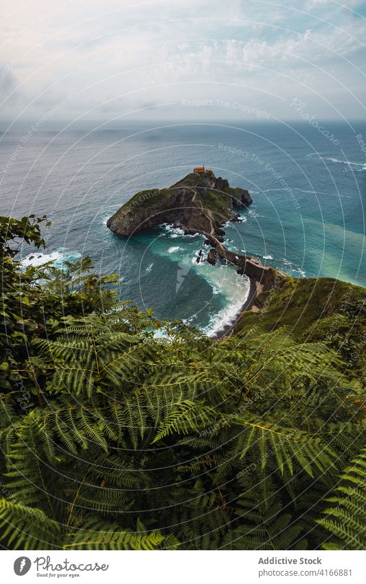 Gekräuseltes Meer in der Nähe von grünen Berg mit Gehweg unter Himmel Berge u. Gebirge Gaztelugatxe Natur Hochland San Juan Meereslandschaft Atmosphäre Laufsteg