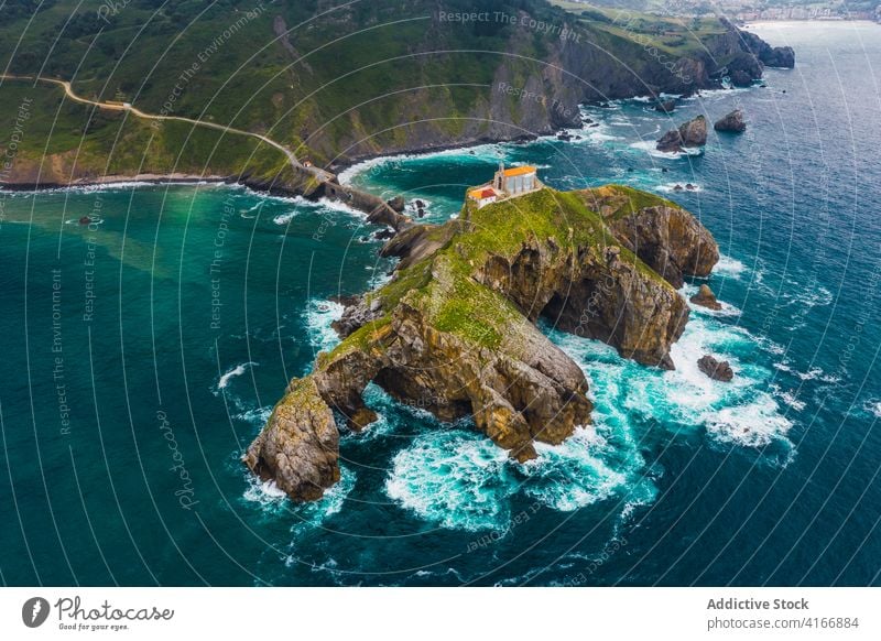 Gekräuseltes Meer in der Nähe von grünen Berg mit Gehweg unter Himmel Berge u. Gebirge Gaztelugatxe Natur Hochland San Juan Meereslandschaft Atmosphäre Laufsteg