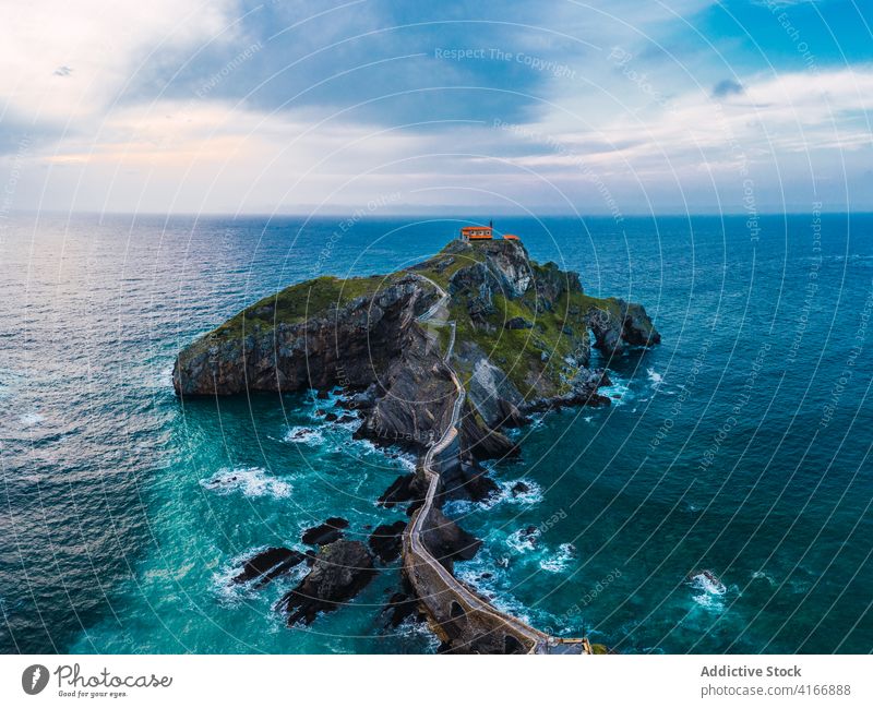 Gekräuseltes Meer in der Nähe von grünen Berg mit Gehweg unter Himmel Berge u. Gebirge Gaztelugatxe Natur Hochland San Juan Meereslandschaft Atmosphäre Laufsteg