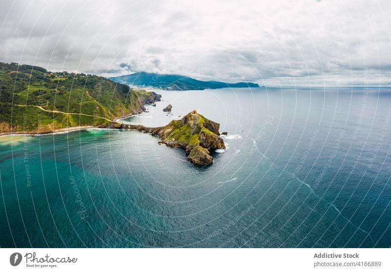 Gekräuseltes Meer in der Nähe von grünen Berg mit Gehweg unter Himmel Berge u. Gebirge Gaztelugatxe Natur Hochland San Juan Meereslandschaft Atmosphäre Laufsteg