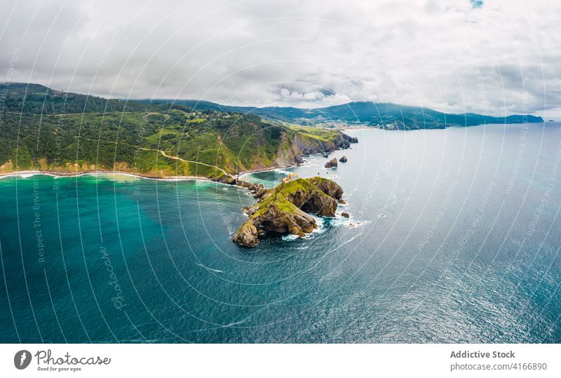 Gekräuseltes Meer in der Nähe von grünen Berg mit Gehweg unter Himmel Berge u. Gebirge Gaztelugatxe Natur Hochland San Juan Meereslandschaft Atmosphäre Laufsteg