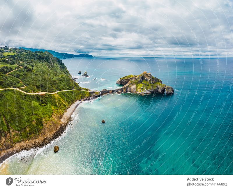 Gekräuseltes Meer in der Nähe von grünen Berg mit Gehweg unter Himmel Berge u. Gebirge Gaztelugatxe Natur Hochland San Juan Meereslandschaft Atmosphäre Laufsteg