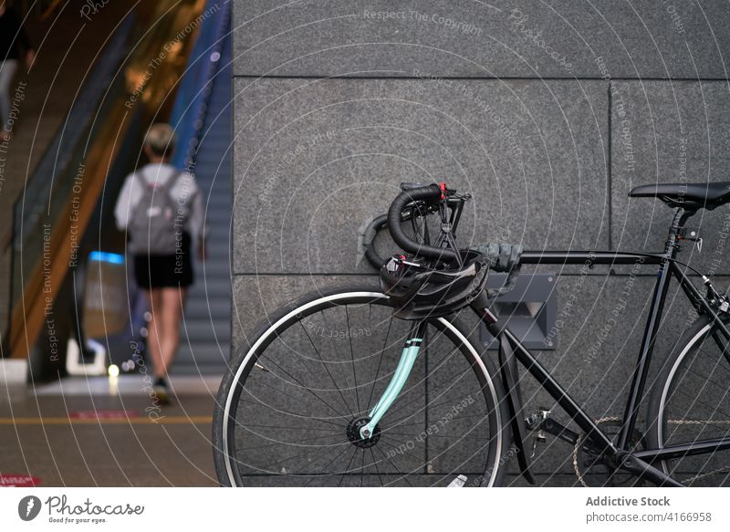 Fahrrad in der Nähe eines Gebäudes auf unscharfem Hintergrund einer gehenden Frau Werkstatt Großstadt Tourismus Szene Tourist Ansicht Straße Stadtbild