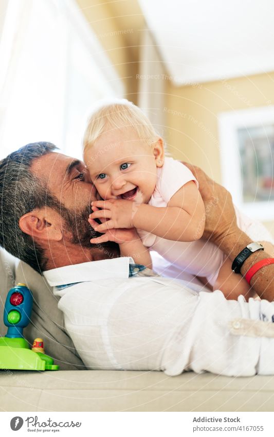 Fröhlicher Papa spielt mit Kleinkind auf Sofa Mann Baby Kuss spielen Liebe Glück Lachen Zusammensein Partnerschaft Vater Bonden Zuneigung Liege heimwärts