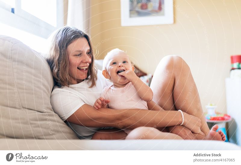 Ruhige Mutter, die ihre kleine Tochter auf dem Sofa umarmt Frau Umarmung Baby Liege heimwärts Glück Liebe Umarmen Augen geschlossen Bonden Pflege Erwachsener