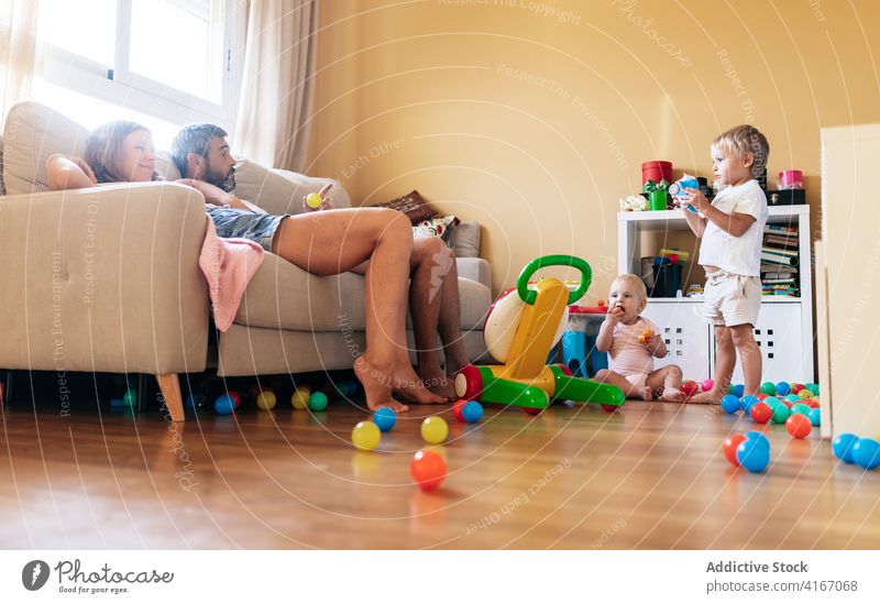 Glückliche Mutter spielt mit Kleinkind Familie Baby Vater heiter spielen Spaß Sofa Ehefrau Ehemann Wohnzimmer Junge Kind Kindheit Elternschaft Zuneigung Freude