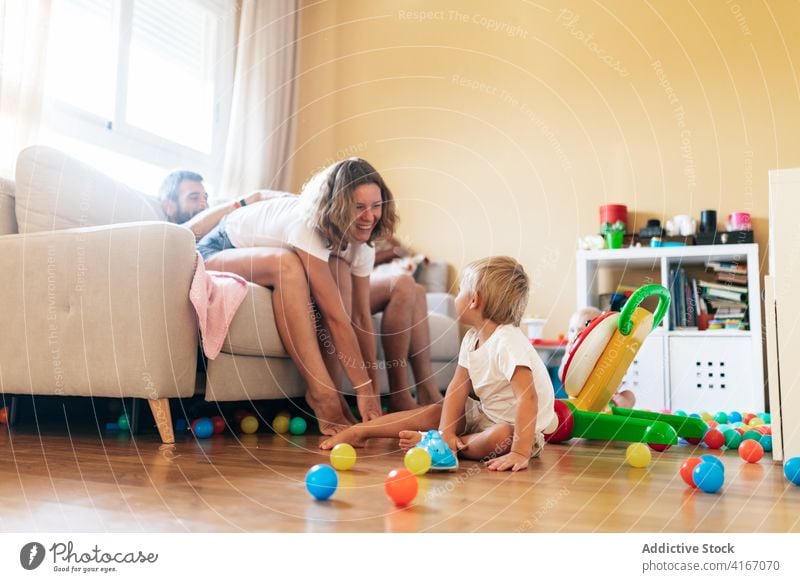 Glückliche Mutter spielt mit Kleinkind Familie Baby Vater heiter spielen Spaß Sofa Ehefrau Ehemann Wohnzimmer Junge Kind Kindheit Elternschaft Zuneigung Freude