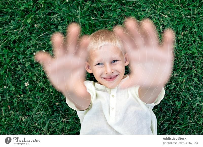 Glücklicher Junge, der sich bei Tageslicht auf dem Rasen ausruht Kind Gras Kälte Wochenende ruhen Vergnügen Hand hinter dem Kopf sich[Akk] entspannen heiter