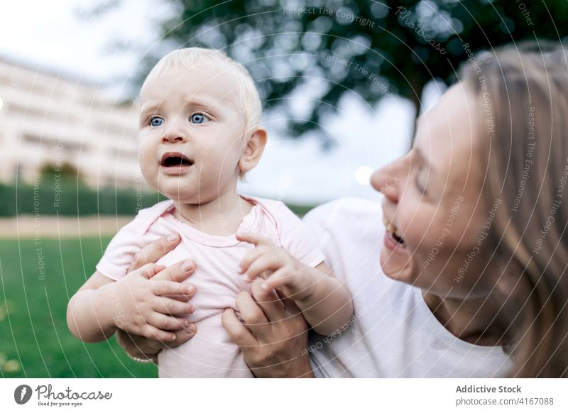 Mutter knuddelt überraschtes Kind im Park bezaubernd niedlich lustig Säugling Umarmen kuscheln Wochenende heiter Glück blond Bonden Zusammensein Kindheit Lachen