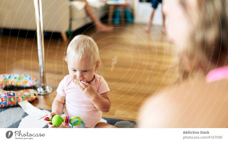 Fröhliche Mutter und Baby Mädchen spielen auf dem Boden Frau Stock heimwärts Glück Spaß haben Spielzeug Grimasse Liebe Tochter Zusammensein bezaubernd jung Kind