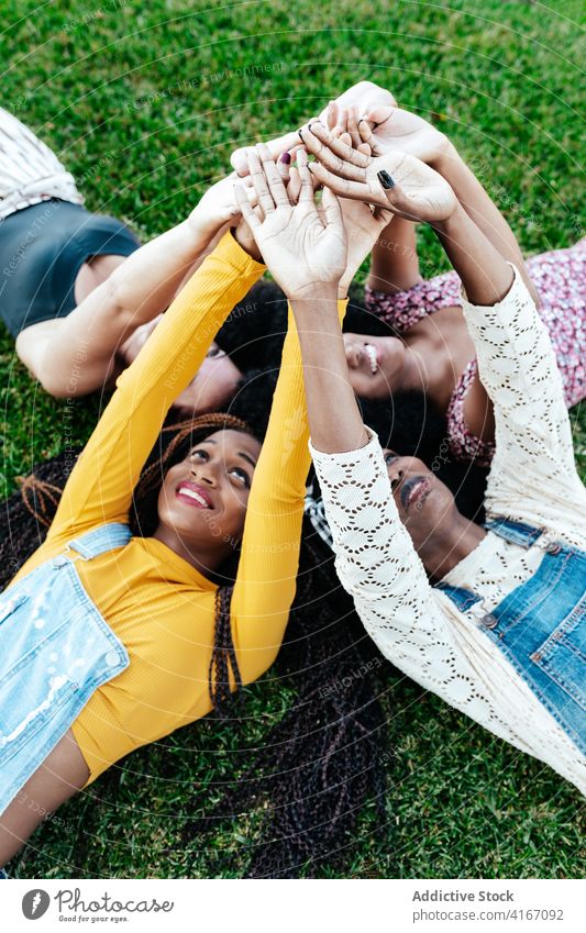 Sorglose diverse Frauen stapeln Hände zusammen Hände stapeln Freundschaft Zusammensein Einheit Unternehmen Lügen Gras sorgenfrei multiethnisch