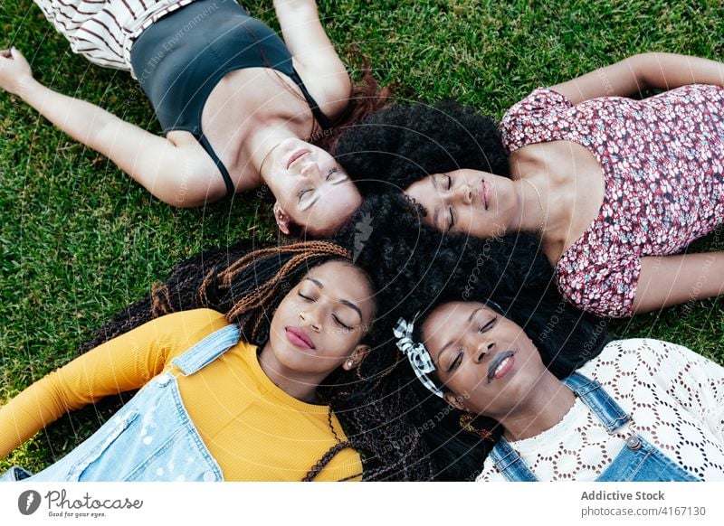 Diverse Frauen liegen auf Gras im Park Freundschaft Lügen positiv Zusammensein freundlich Bonden jung multiethnisch rassenübergreifend vielfältig schwarz