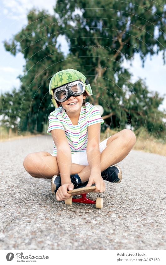 Glücklicher Junge auf Skateboard in Schutzbrille Schutzhelm Spaß haben sorgenfrei Kindheit aufgeregt Inhalt Straße stylisch Bekleidung Brille dekorativ Sommer