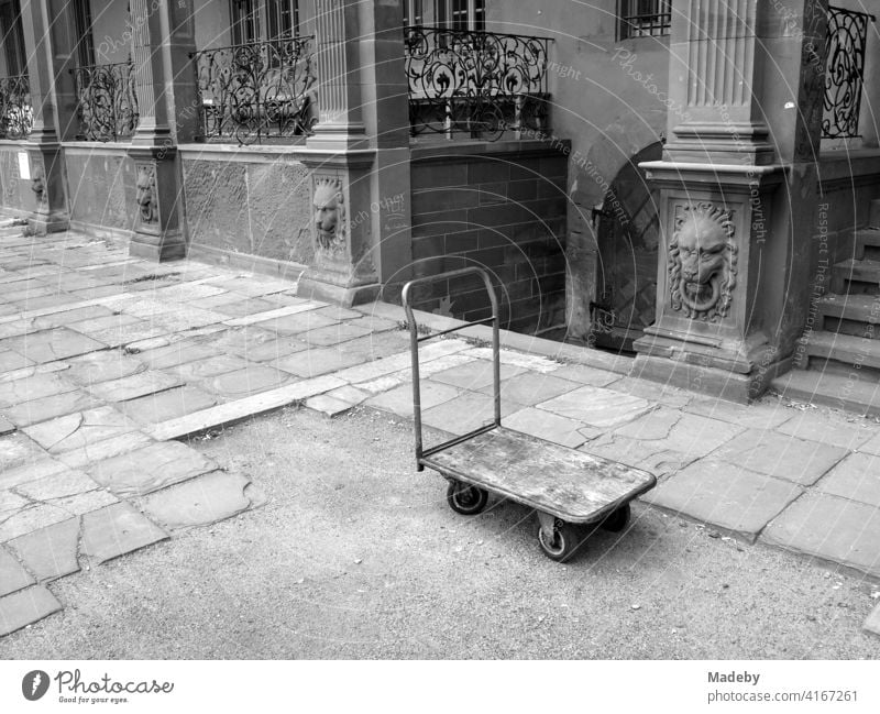 Alter Plattformwagen im Innenhof vor dem Ysenburger Schloss in Offenbach am Main in Hessen, fotografiert in klassischem Schwarzweiß Magazinwagen Wagen Karre