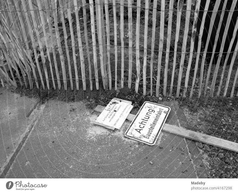 Umgestürztes Schild an einer Baustelleneinfahrt vor einem Holzzaun am Hafengarten in Offenbach am Main in Hessen, fotografiert in klassischem Schwarzweiß