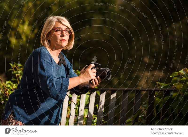 Fotografin mit Kamera und Naturaufnahmen Frau Wald Zaun fotografieren Fotoapparat schießen einfangen Umwelt Fotografie Hobby Künstler kreativ Arbeit Erwachsener