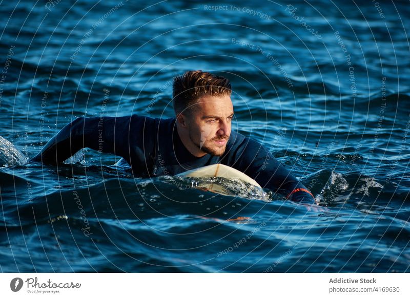 Mann schwimmt auf Surfbrett im Meer Surfer schwimmen MEER Brandung Surfen Neoprenanzug Aktivität Sommer männlich sonnig blau Wasser Sport Athlet Erholung Hobby