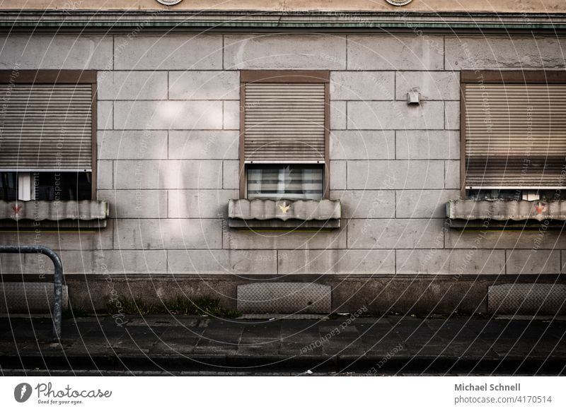 Fassade und Fenster eines alten, grauen Wohnhauses trist Tristesse Rolladen Gebäude Architektur Außenaufnahme drei