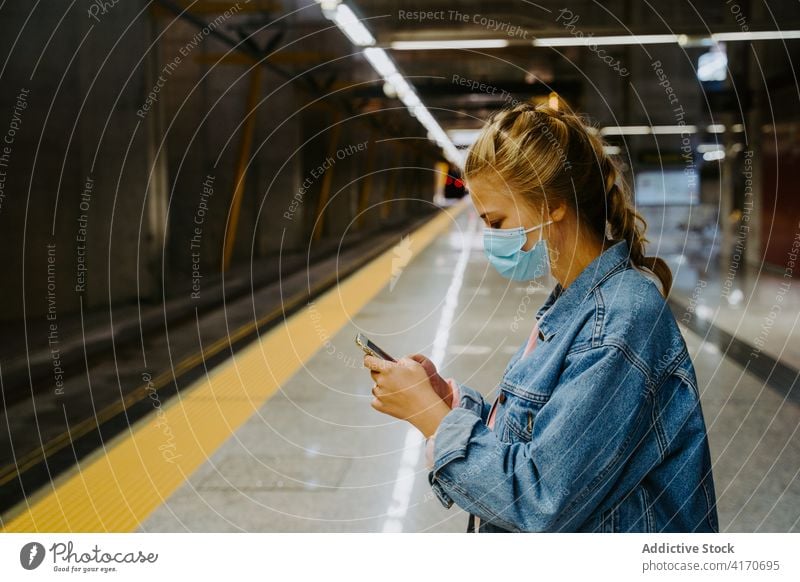 Frau mit Maske auf Smartphone am Bahnhof Passagier benutzend Funktelefon Coronavirus Eisenbahn Texten Station Reise COVID COVID19 Bund 19 Zug Verkehr Gerät